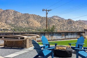 Un espace extérieur aménagé avec des chaises Adirondack et un jacuzzi, offrant une vue sur un paysage montagneux.