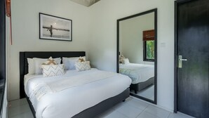 A bedroom with a bed, a large mirror, and a framed picture on the wall. - The Aryana Estate in Seminyak (Keroboken Kelod)