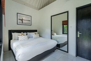 A bedroom with a bed, a large mirror, and a framed picture on the wall. - The Aryana Estate in Seminyak (Keroboken Kelod)