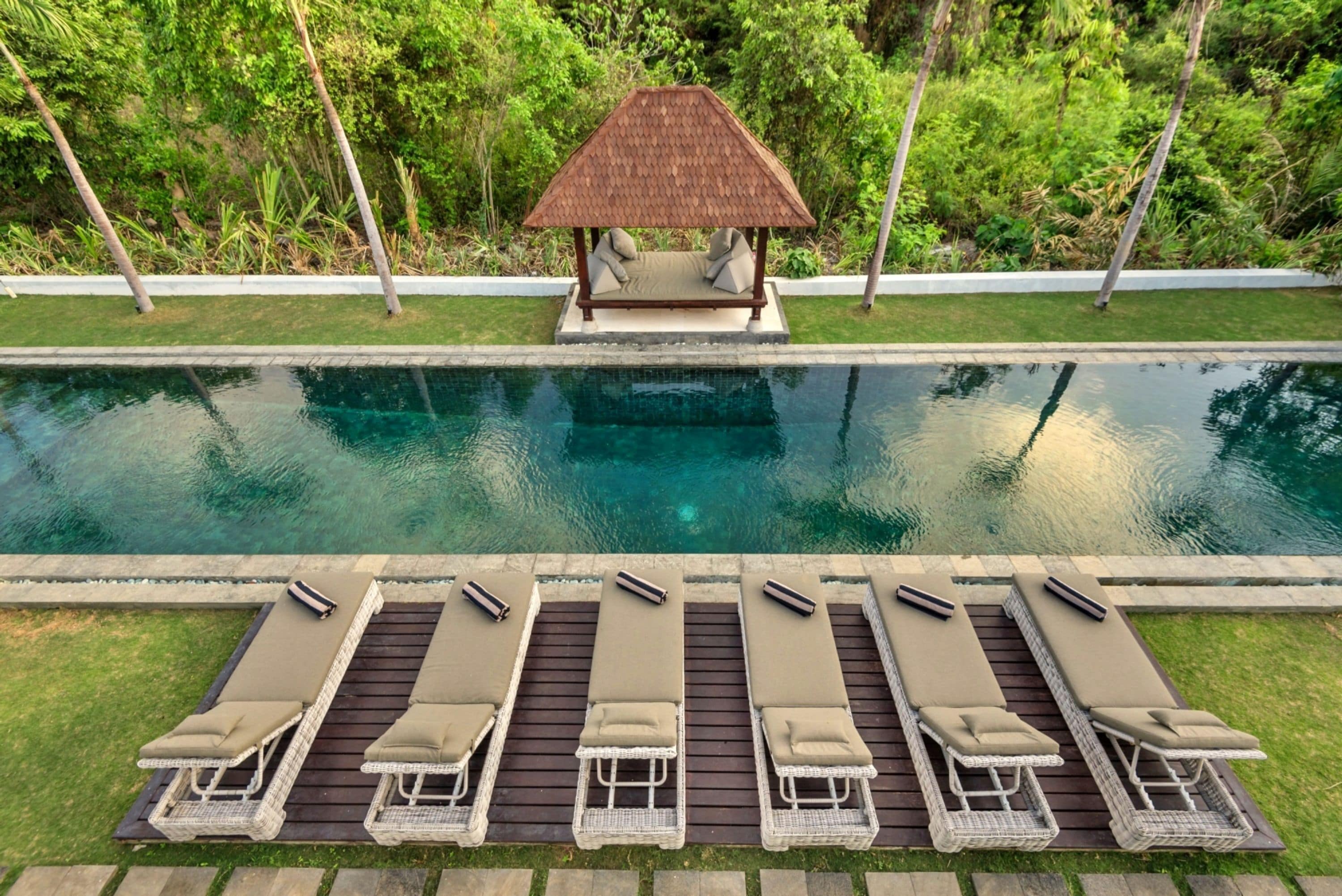 A pool with lounge chairs and a gazebo.