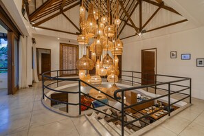 A spacious interior with a central staircase, a dining area, and a ceiling with hanging light fixtures. - Jessica Estate in Canggu (Tibubeneng)