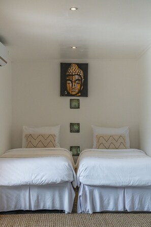 A bedroom with two beds, a ceiling light, and a Buddha painting. - Jessica Estate in Canggu (Tibubeneng)