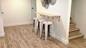 Una habitación con piso de madera, una pared blanca con un plato decorativo y una escalera.