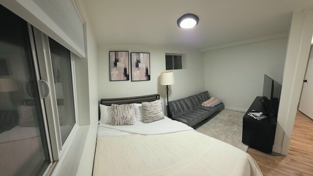 Una habitación de hotel con cama, sofá, televisión y ventana.