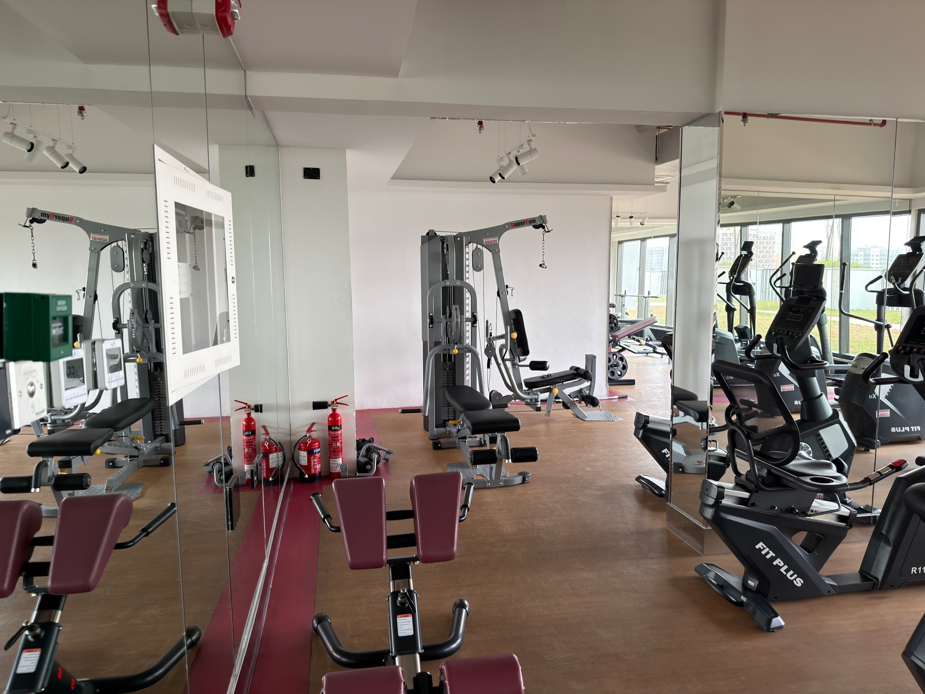 Ein Fitnessstudio mit unterschiedlichen Trainingsgeräten, darunter Laufbänder, Crosstrainer und Kraftgeräte.