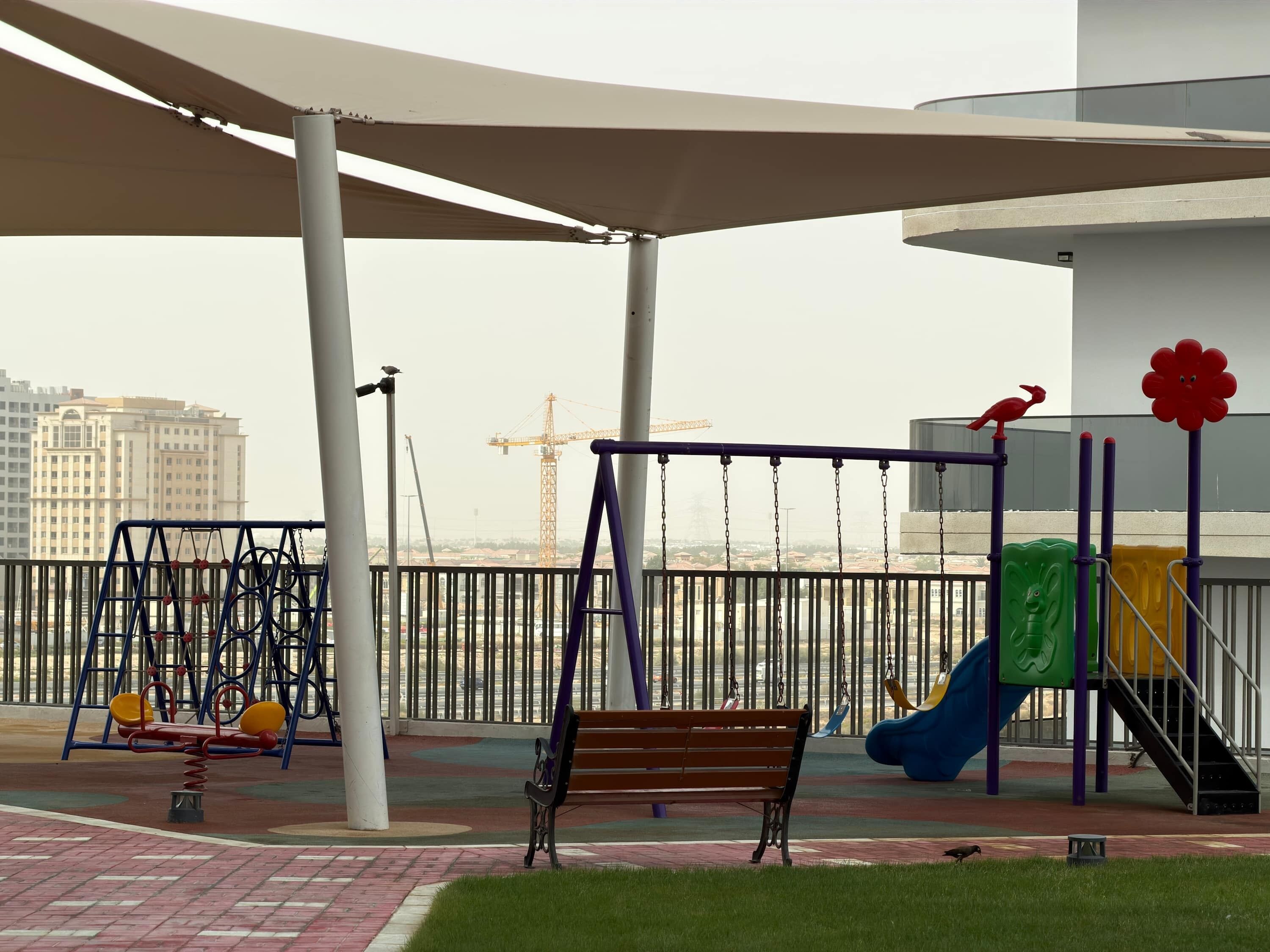 A playground with swings, a slide, and a bench.