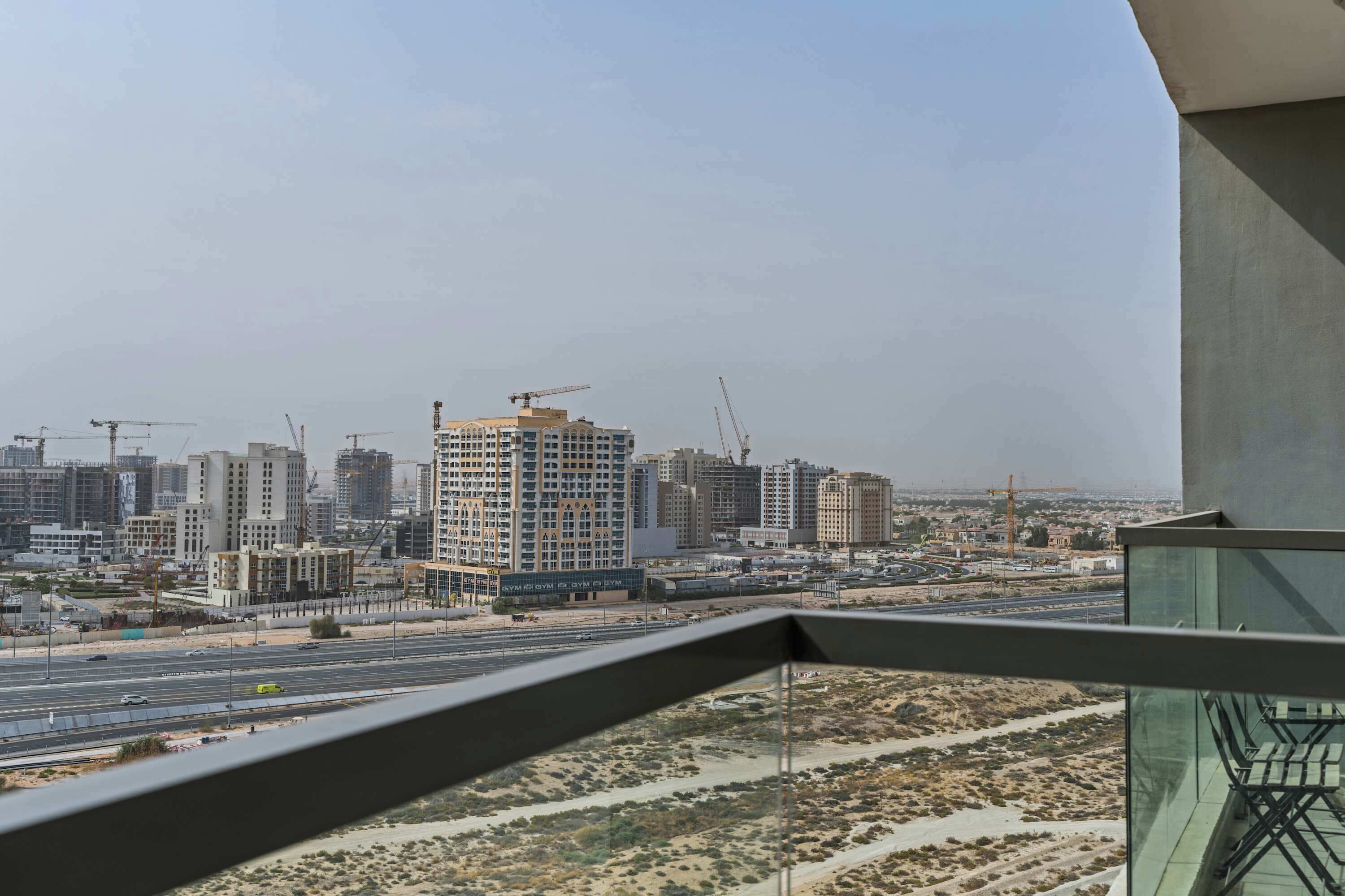 A cityscape with multiple high-rise buildings, some under construction, and a clear view of the surrounding desert landscape.