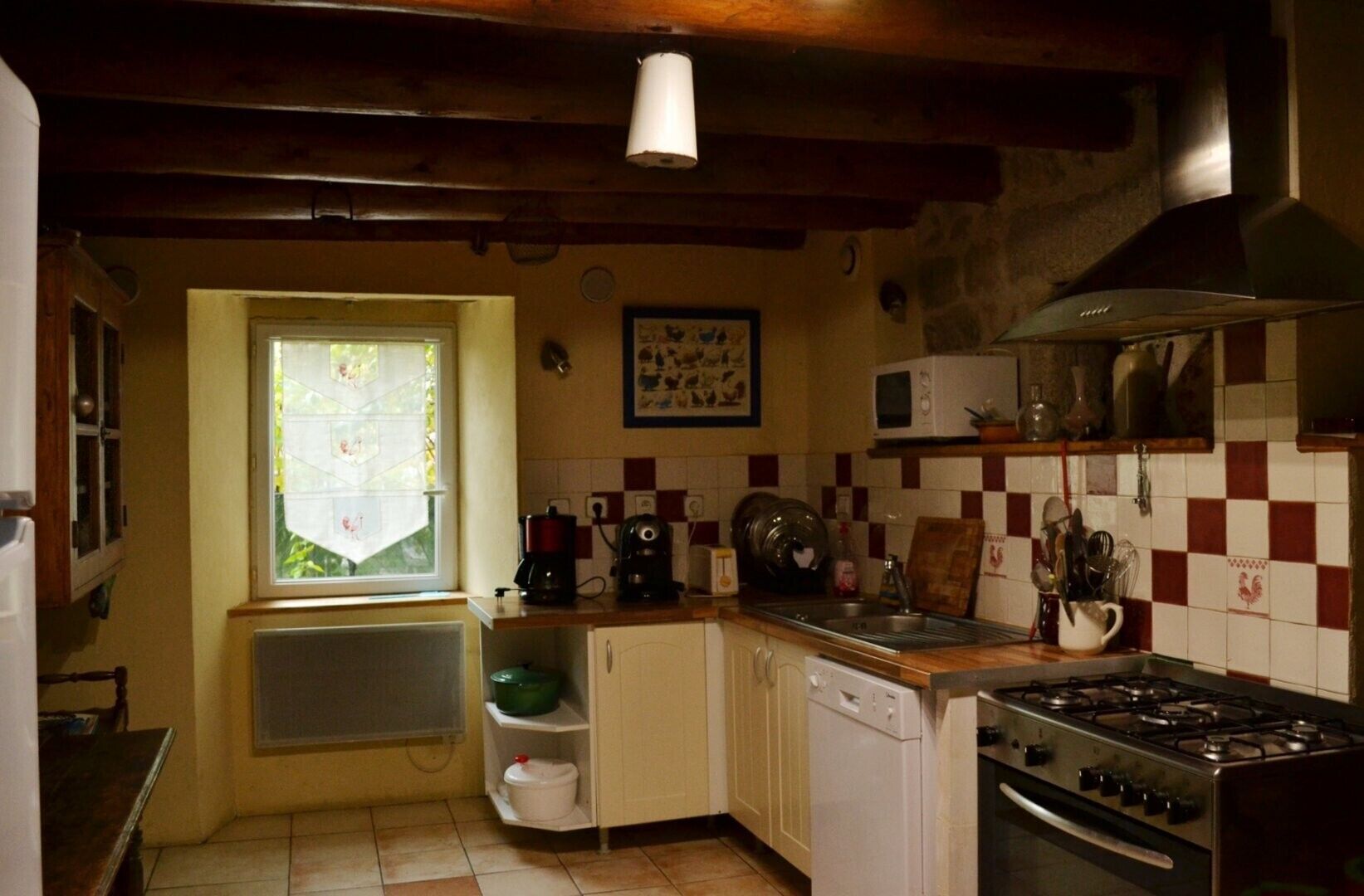 Una cucina con finestra, microonde, fornello e lavastoviglie.