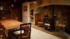 A rustic dining area with a wooden table and chairs, a stone fireplace, and a vintage radio.