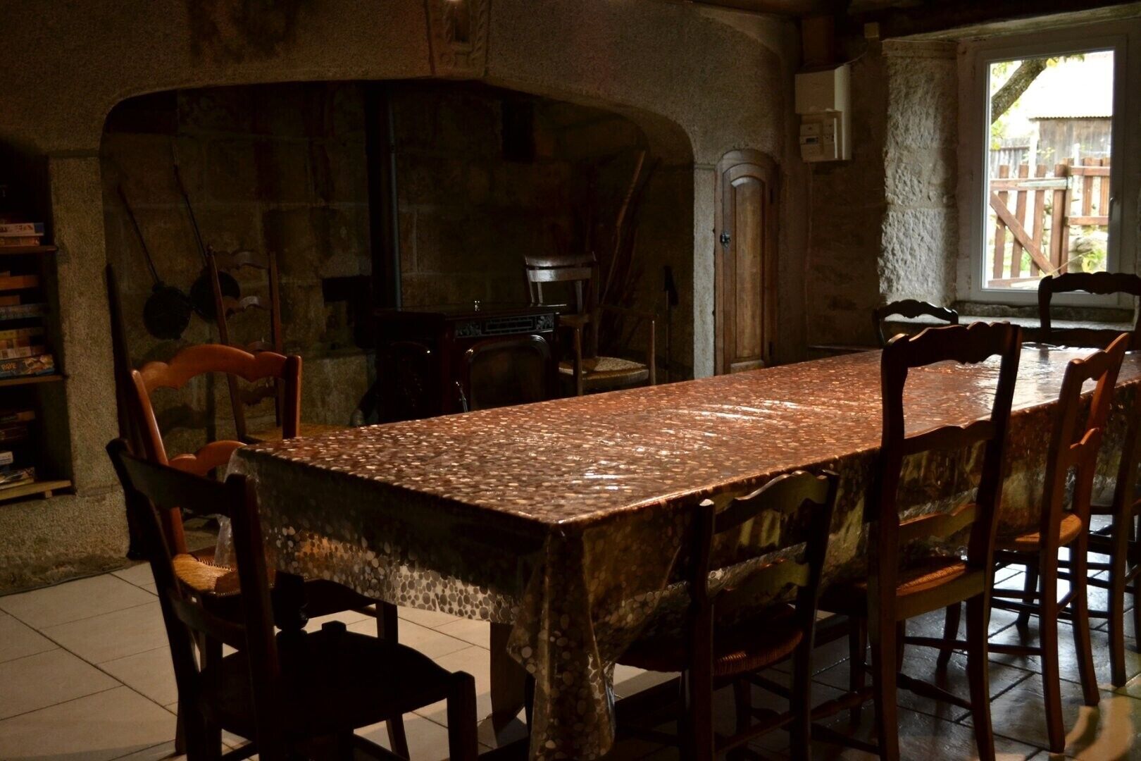 Un coin repas rustique agrémenté d’une arche en pierre, de chaises en bois et d’un sol carrelé.