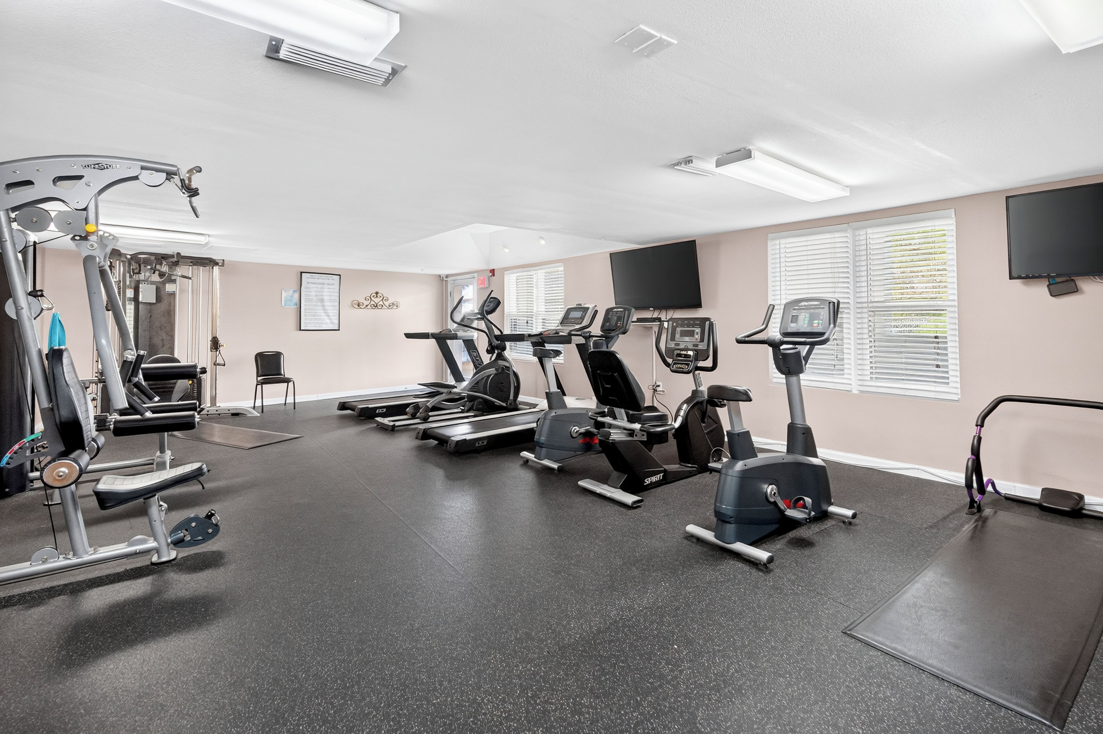 A gym with various exercise equipment, including treadmills, stationary bikes, and weight machines.