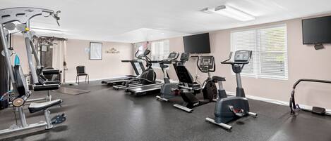 A gym with various exercise equipment, including treadmills, stationary bikes, and weight machines.