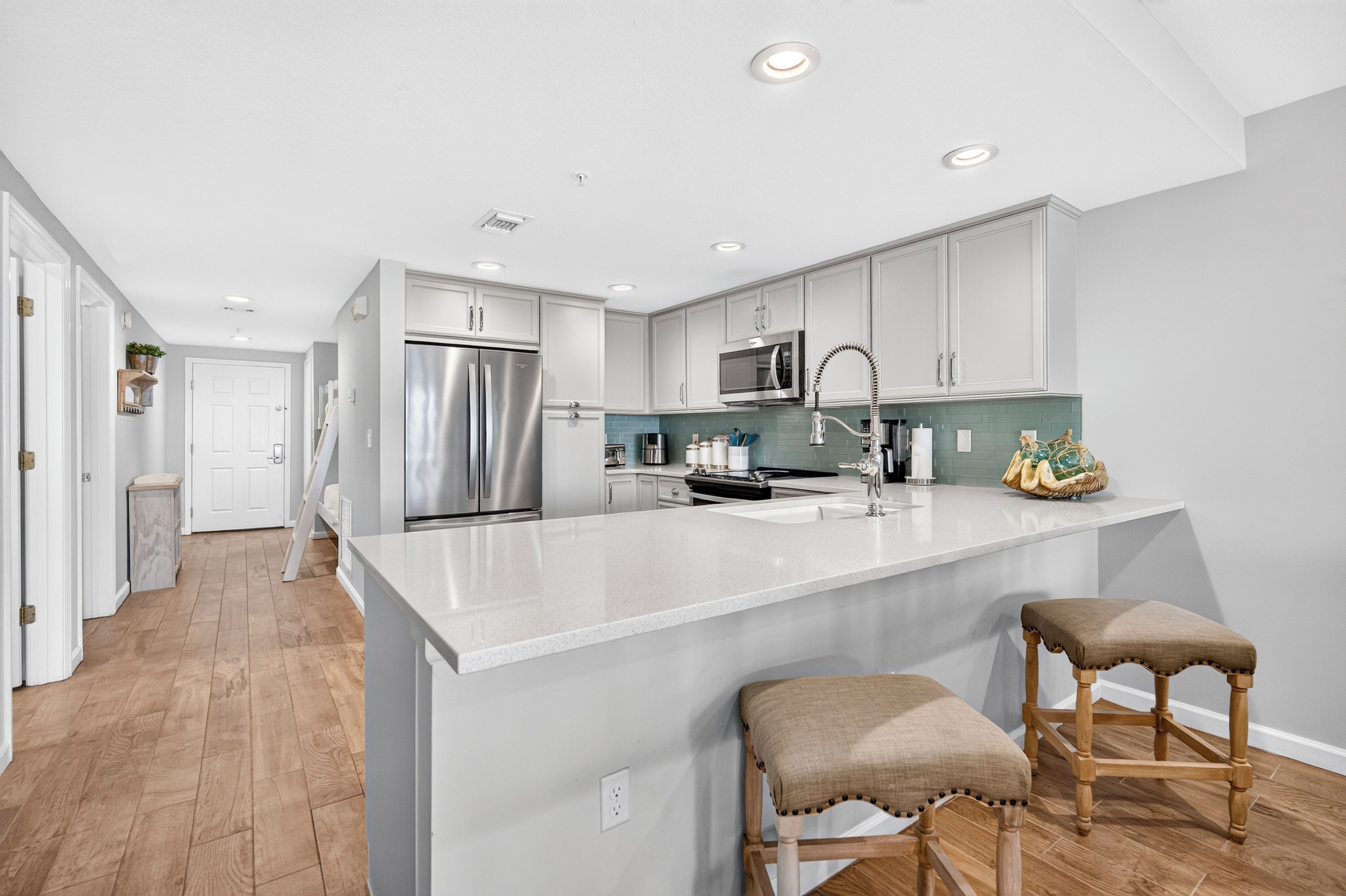 A modern kitchen with white cabinets, stainless steel appliances, and a large island with stools.