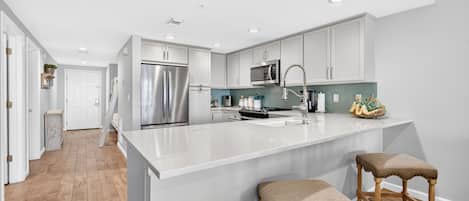 A modern kitchen with white cabinets, stainless steel appliances, and a large island with stools.