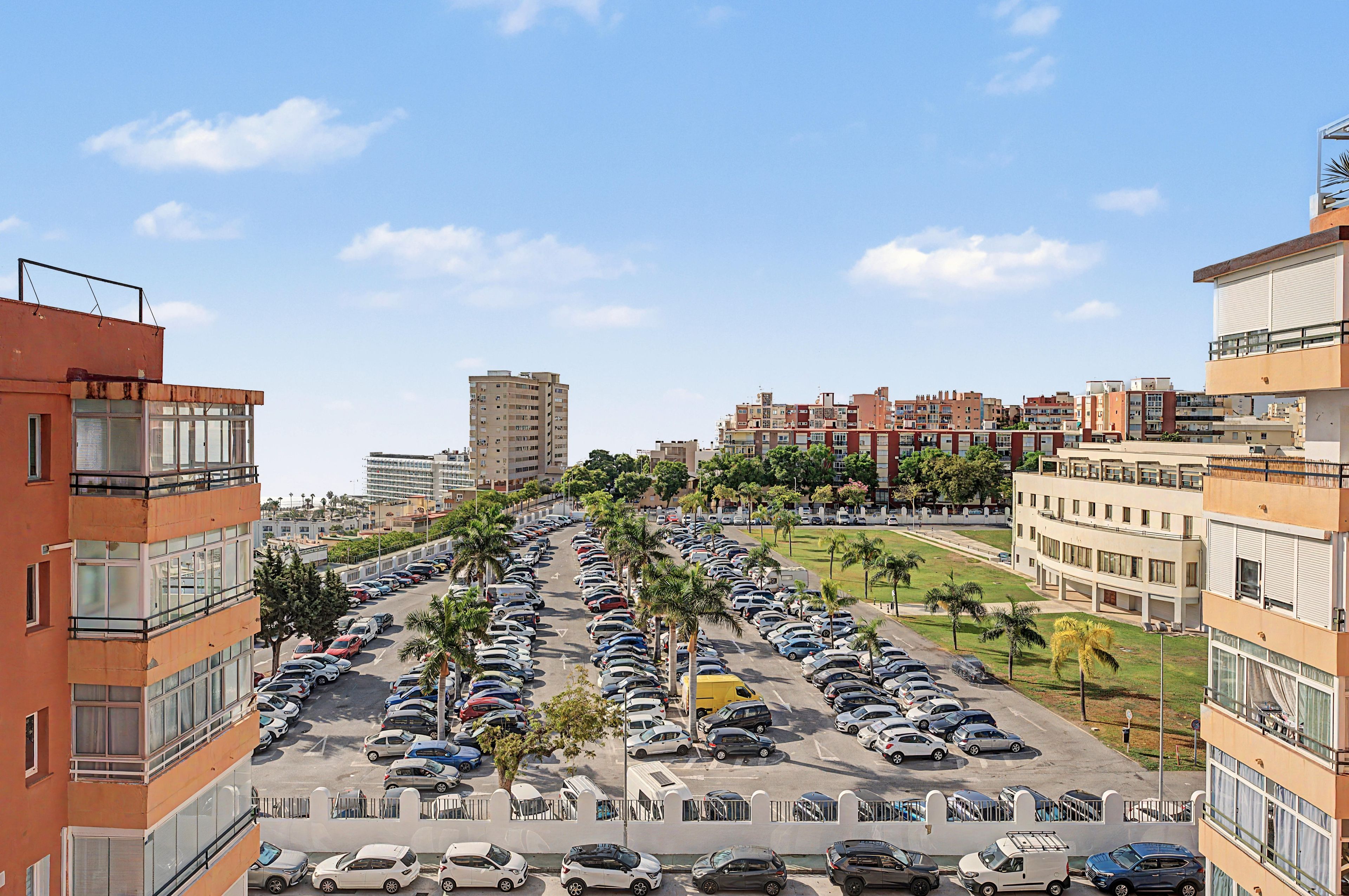 Un estacionamiento de varios niveles con automóviles estacionados en diferentes plantas, rodeado de edificios residenciales.