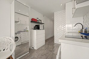 A modern kitchen with white cabinetry, a built-in washing machine, and a countertop with a sink. - Costa del Sol Apartment with Balcony, Wi-Fi, Air Conditioning (Torremolinos)