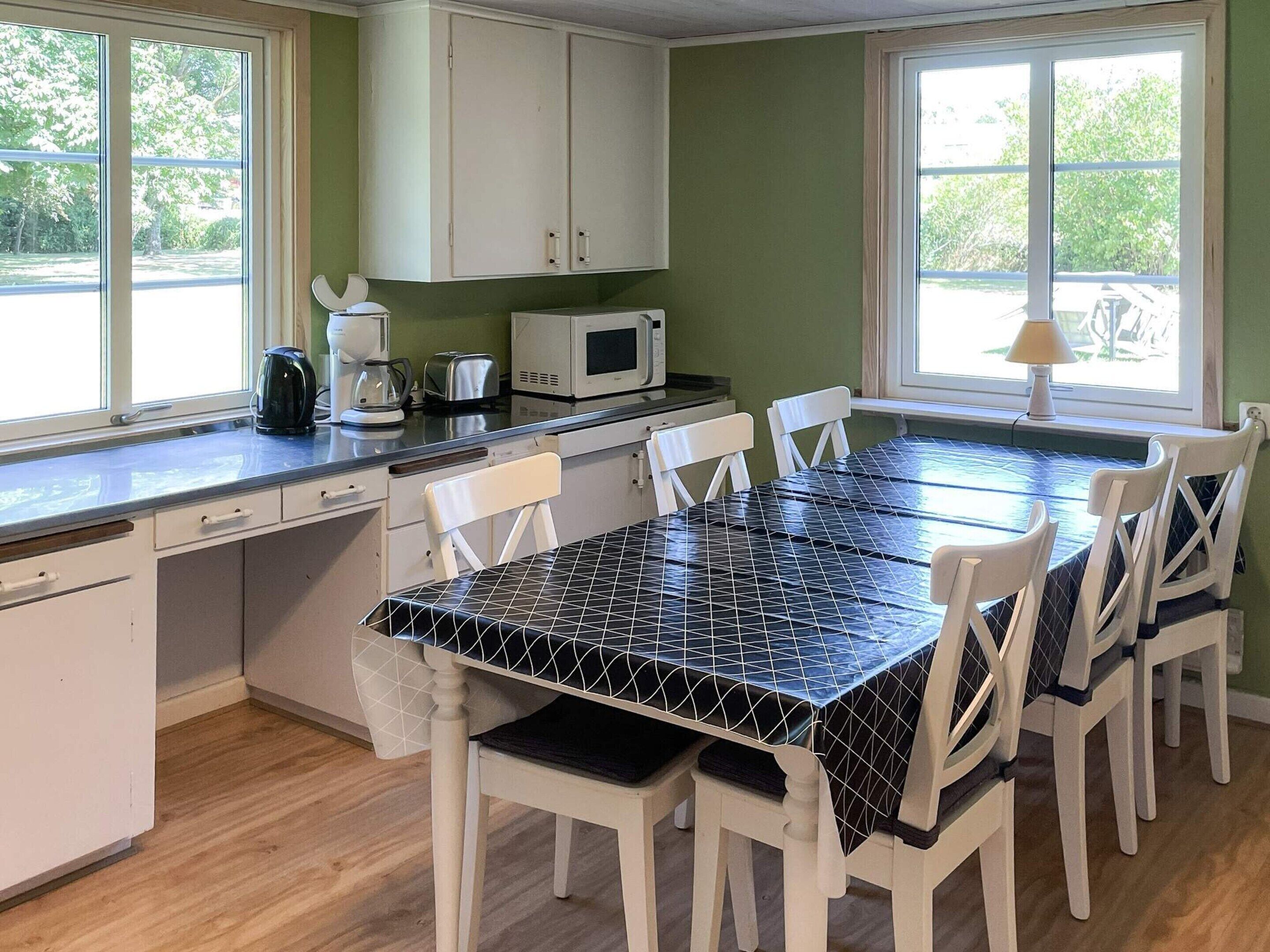 A kitchen with a dining table, chairs, cabinets, a microwave, and a coffee maker.
