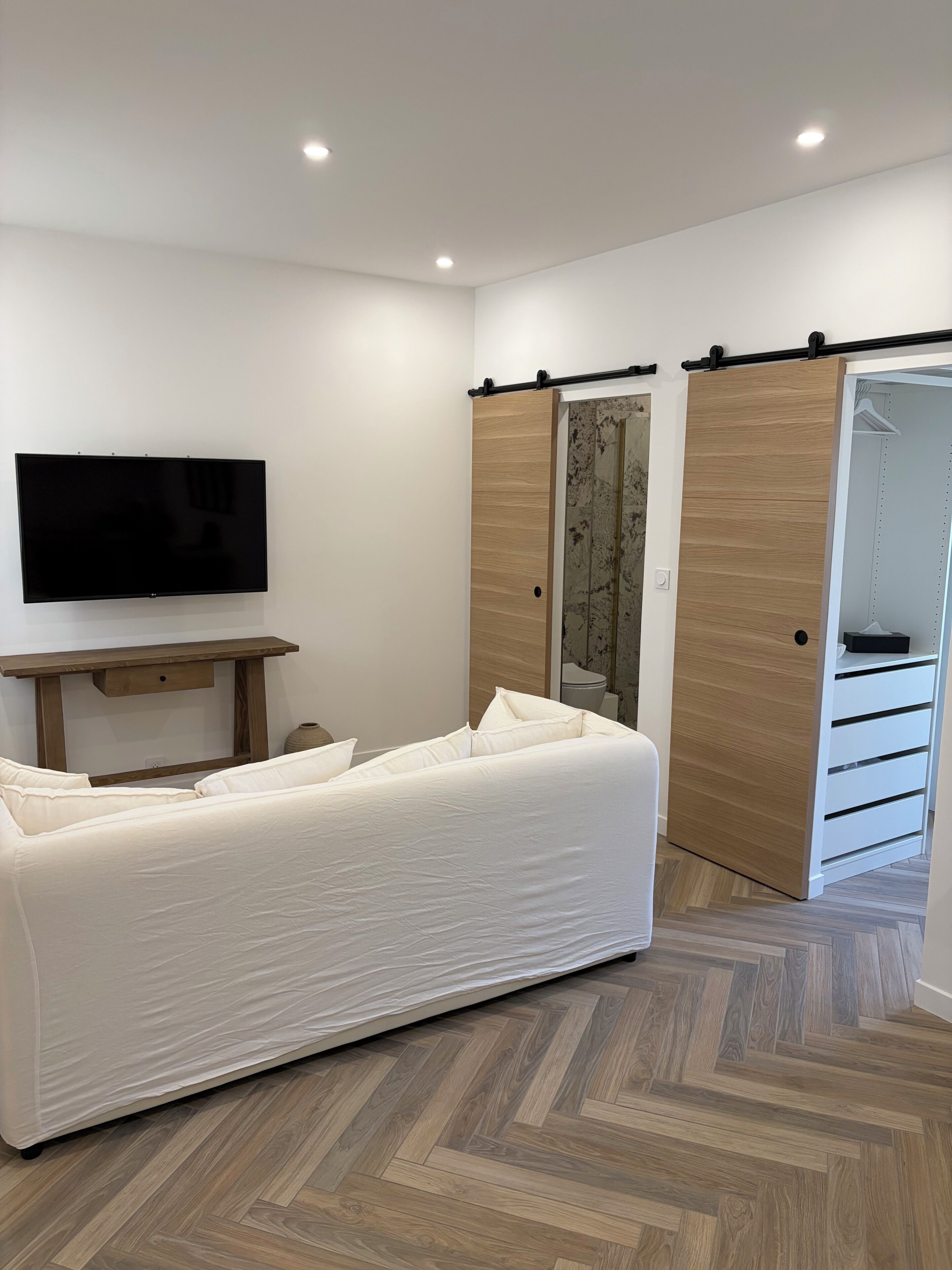 Une chambre moderne équipée d’un lit, d’un téléviseur à écran plat, d’un bureau en bois et d’une armoire aux portes coulissantes.