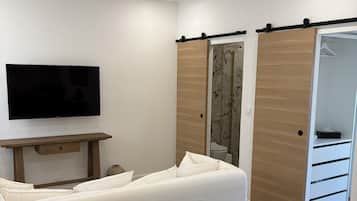 Une chambre moderne équipée d’un lit, d’un téléviseur à écran plat, d’un bureau en bois et d’une armoire aux portes coulissantes.