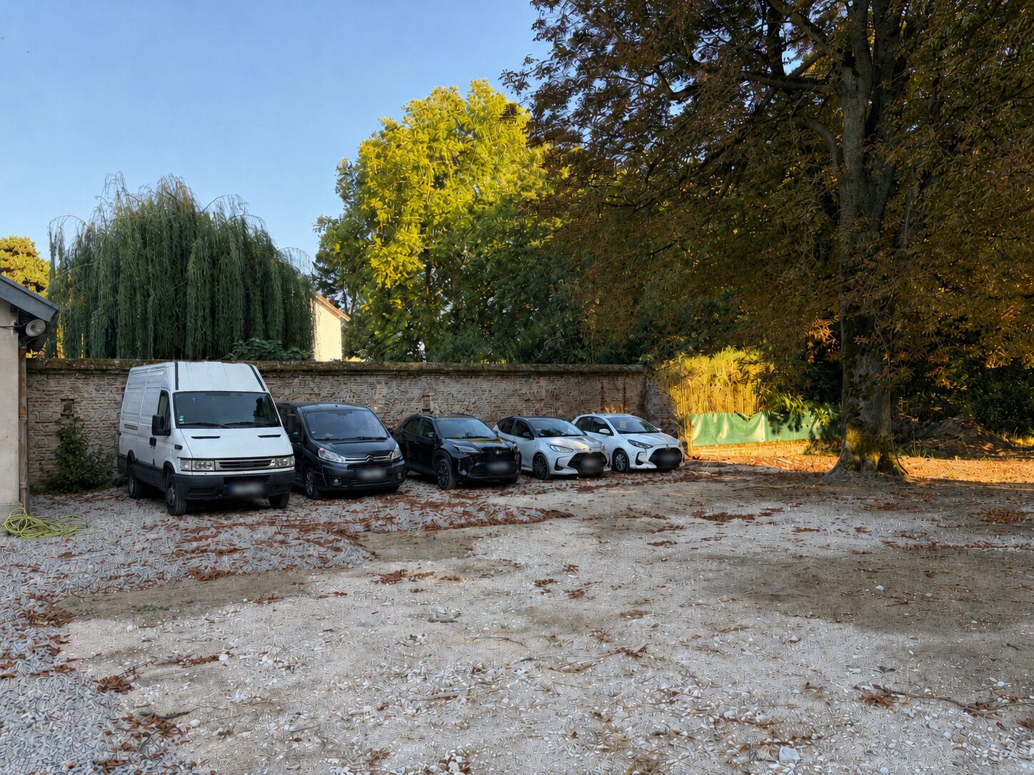 A parking area with a white van and several cars parked.