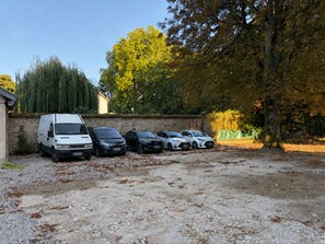 A parking area with a white van and several cars parked.