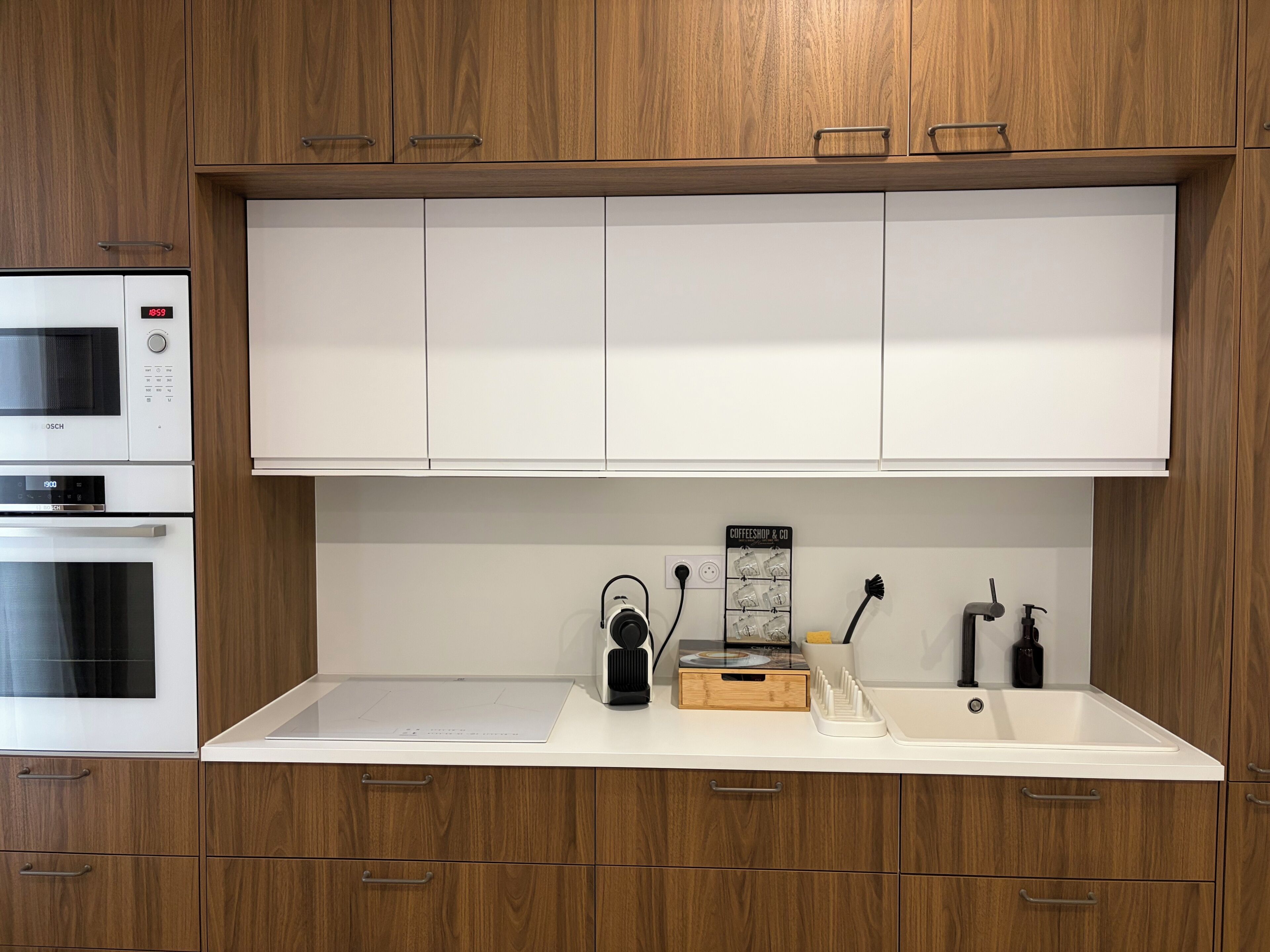 A kitchen with wooden cabinets, a microwave, an oven, a coffee machine, and a sink.