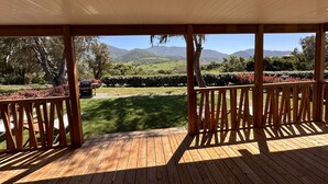 A wooden deck with a view of a landscaped garden and distant mountains. - The Scandola Reserve (Appietto)