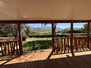 A wooden deck with a view of a landscaped garden and distant mountains.