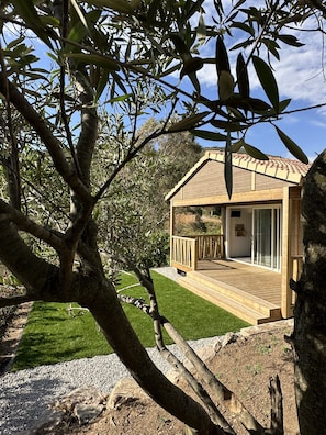 Ein Holzhaus mit Terrasse, umgeben von Bäumen und einem gepflegten Rasen.