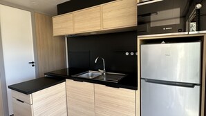 A modern kitchen with a stainless steel refrigerator, a black countertop, and wooden cabinetry. - The Lava Hills - Girolata (Appietto)