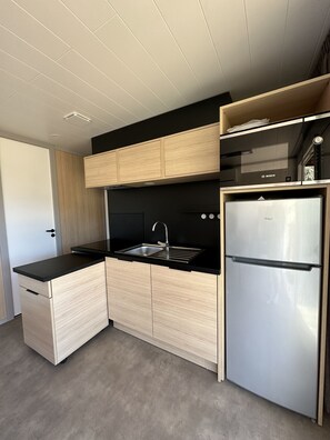 Eine moderne Küche mit einem Edelstahl-Kühlschrank, einer schwarzen Arbeitsplatte und Holzschränken.
