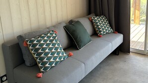 A grey sofa with patterned cushions and a ceiling-mounted air conditioner. - The Lavezzi Islands - 4-Bedroom Chalet (Appietto)