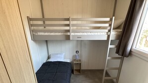 A bunk bed room with a wooden wardrobe, a small bedside table, and a window with curtains. - The Lavezzi Islands - 4-Bedroom Chalet (Appietto)