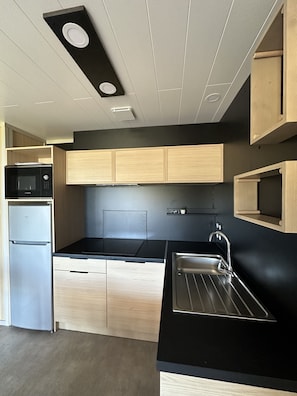 A modern kitchen with built-in appliances, wooden cabinets, and a black countertop.