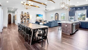 A spacious kitchen with a central island, modern appliances, and a dining area with chairs. - The Big Top ~ Pool, Spa & Walk to St. Armands (Sarasota)