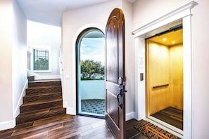 Ein modernes Interieur mit einer Holztreppe, einem großen Bogenportal und einem Aufzug.