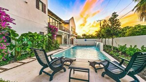 A swimming pool with lounge chairs, surrounded by greenery and a building. - The Big Top ~ Pool, Spa & Walk to St. Armands (Sarasota)