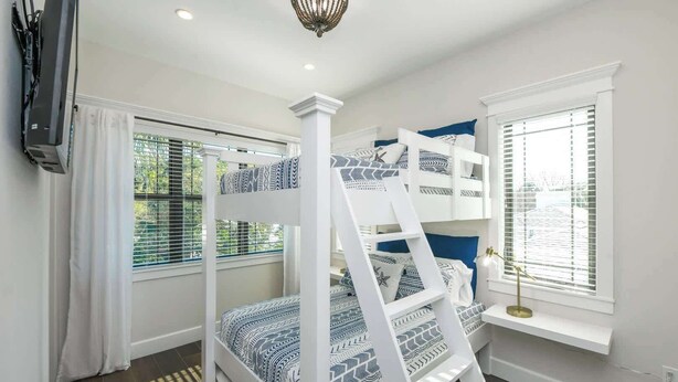 A bunk bed room with a ladder, a window with blinds, and a small table with a lamp. - The Big Top ~ Pool, Spa & Walk to St. Armands (Sarasota)