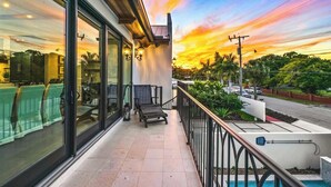 A balcony with a view of a sunset, a pool, and a street with cars. - The Big Top ~ Pool, Spa & Walk to St. Armands (Sarasota)