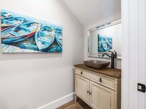 A bathroom with a wooden vanity, a large mirror, and a painting of boats on the wall. - The Shore House ~ Lido Key ~ Pool/Spa (Sarasota)