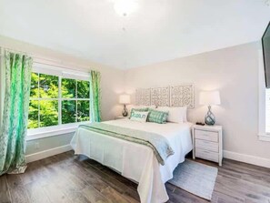 A bedroom with a bed, nightstands, a window with curtains, and artwork on the wall. - The Shore House ~ Lido Key ~ Pool/Spa (Sarasota)
