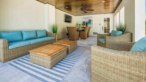 An outdoor living area with wicker furniture, a ceiling fan, and a view into the house. - The Shore House~St Armands, Lido Beach, Pool (Sarasota)