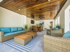 An outdoor living area with wicker furniture, a ceiling fan, and a view into the house. - The Shore House~St Armands, Lido Beach, Pool (Sarasota)