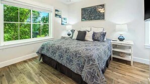 A bedroom with a large bed, a ceiling fan, a window with a view of greenery, and a wall-mounted TV. - The Shore House~St Armands, Lido Beach, Pool (Sarasota)