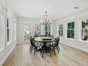 A spacious dining area with a round table and chairs, large windows, and a chandelier. - The Shore House ~ Lido Key ~ Pool/Spa (Sarasota)