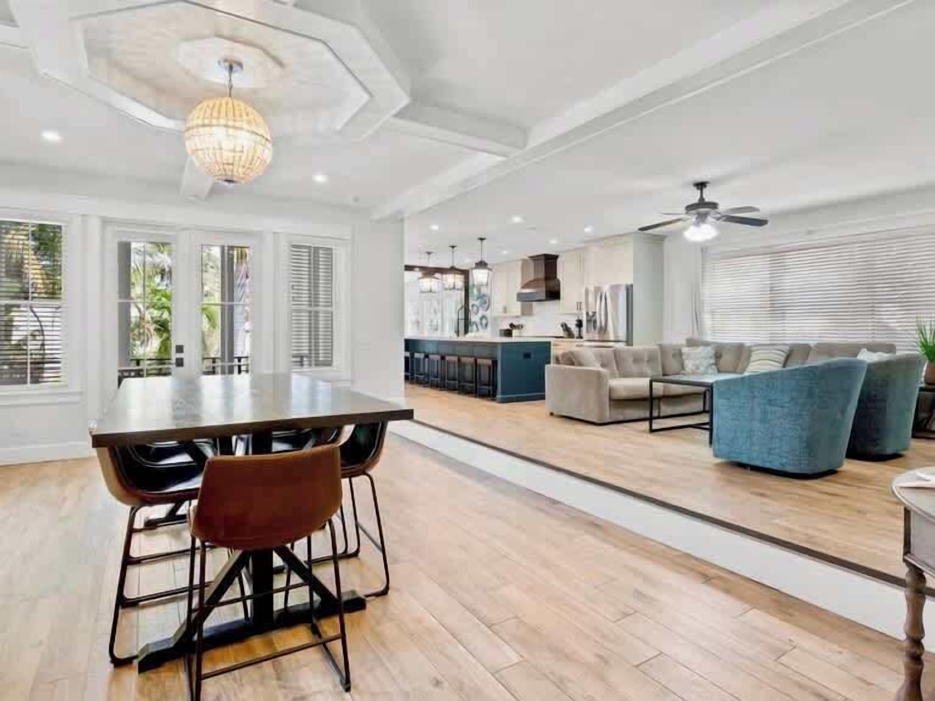 A spacious living area with a dining table, sofas, and a kitchen in the background.