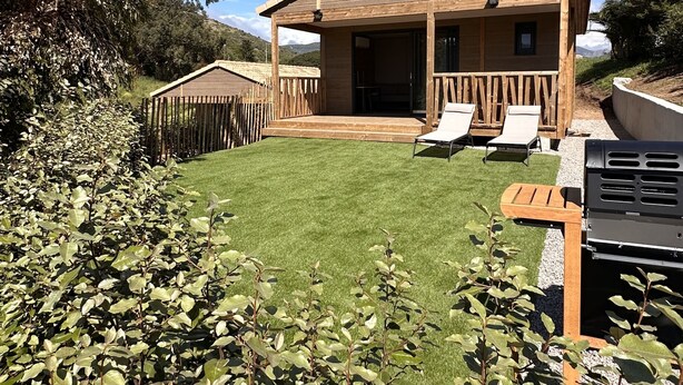 A wooden cabin with a covered patio, a lawn, and a barbecue grill. - Porto Chalet - Cozy & Modern, Sleeps 6 (Appietto)