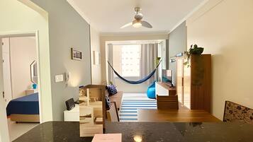 Una sala moderna con una hamaca, un aparador de madera y un tapete azul a rayas.