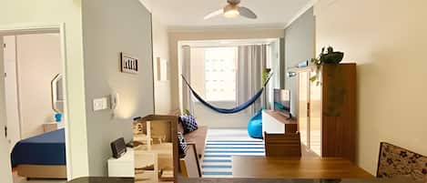 Un salon moderne avec un hamac, un meuble en bois et un tapis à rayures bleues.