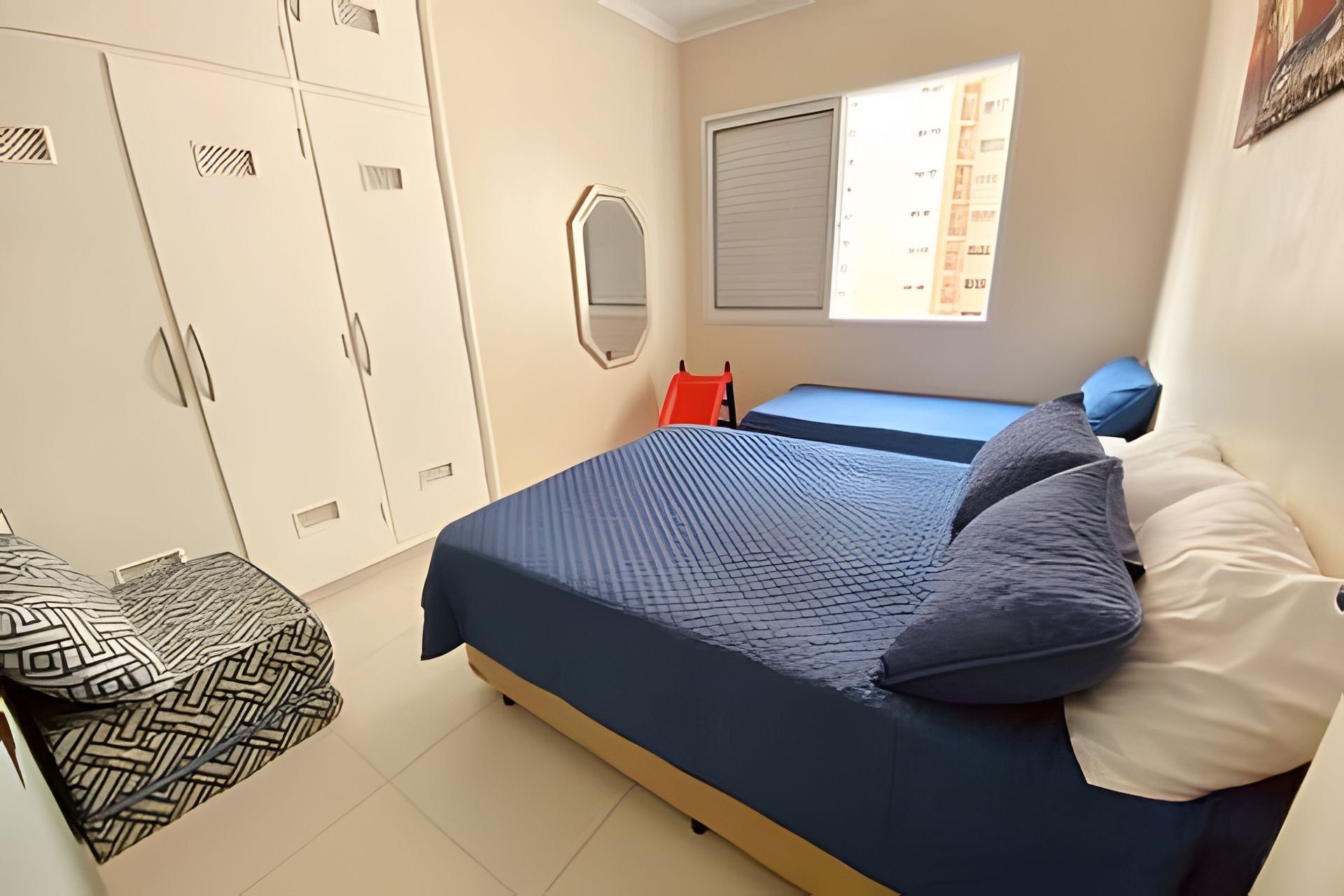 Une chambre à coucher avec un lit, une armoire, une fenêtre et une chaise.